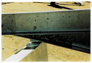 Description: Gross dross puddle trapped in corner of fabrication.Cause: Upward-facing universal section picked up dross from bottom of zinc kettle – unable to drain out on withdrawal. Remedy: Mechanically remove if possible or re-galvanize to melt-out dross. Costly waste for galvanizer because of the dross value. Durability unaffected because dross has similar anticorrosive properties to zinc.