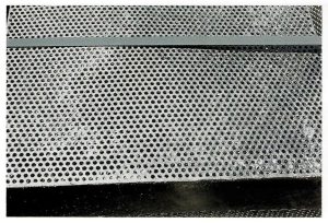 Description: Zinc film clogging or partly bridging holes in screen / filter unit.Cause: The surface tension of molten zinc is high and will not drain easily from holes under 8mm in diameter. Remedy: Make holes as large as possible. Active fettling on bath and using vibrators on galvanizing cranes will minimise hole clogging